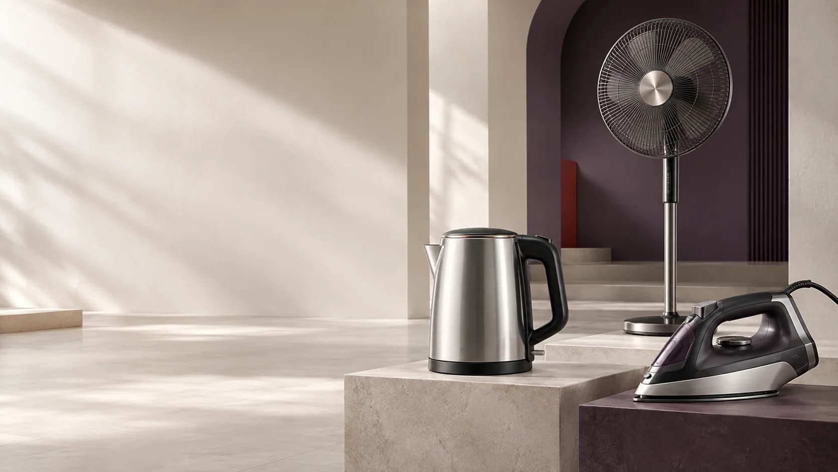 Editorial appliance composition with a kettle, iron and pedestal fan in a warm architectural setting